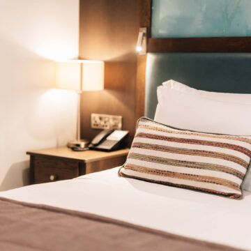Elegant hotel room with plush bedding, ambient lighting, and bedside amenities for a comfortable stay.