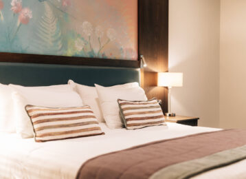 Elegant hotel room with cosy bed, modern artwork, and ambient lighting for a relaxing stay near city centre attractions.