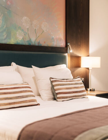 Elegant hotel room with cosy bed, modern artwork, and ambient lighting for a relaxing stay near city centre attractions.