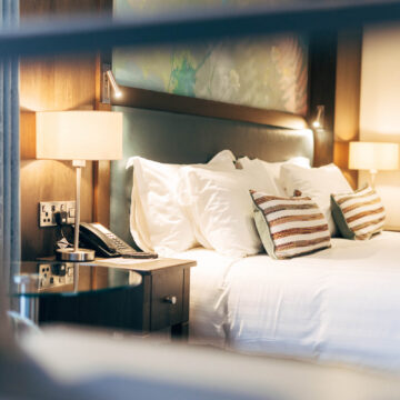 Elegant hotel room with plush bed, soft lighting, and modern decor offering a cosy, relaxing stay for guests.