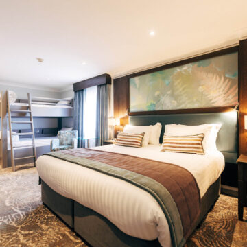 Spacious double room with plush bedding, modern decor, bunk beds, cosy lighting, and a serene atmosphere at a family-friendly hotel.