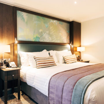 Stylish hotel room with king-sized bed, soft lighting, cosy pillows, and modern decor for a relaxing stay.