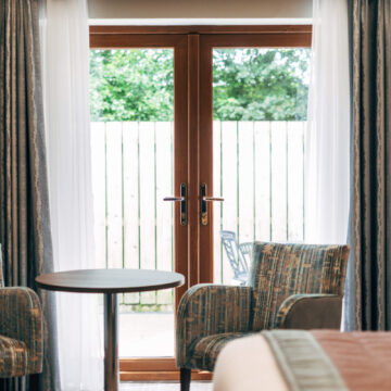 Charming hotel room with cosy seating, large window, and garden view; perfect for a relaxing stay.