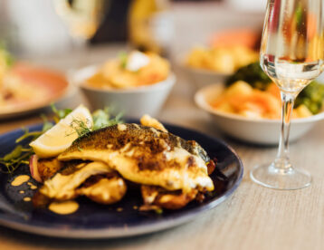 Elegant dining with gourmet fish dish and sparkling wine at a luxurious hotel restaurant, perfect for romantic evenings.