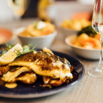 Elegant dining with gourmet fish dish and sparkling wine at a luxurious hotel restaurant, perfect for romantic evenings.