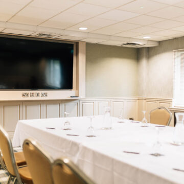 Elegant conference room with a large screen, cosy seating, and natural light for productive meetings or events.