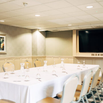 Spacious hotel conference room with large TV, elegant seating, and art on the wall, ideal for meetings and events.