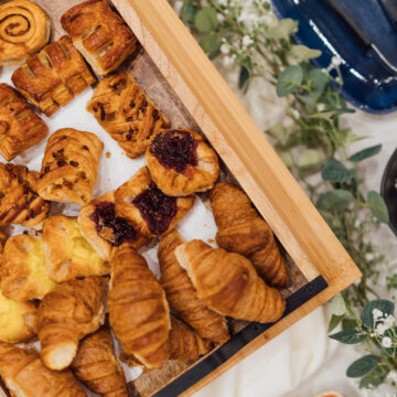 Luxurious hotel breakfast with fresh croissants, pastries, cream, and jam amidst elegant décor.