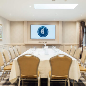 Bright meeting room with skylight, elegant décor, and horseshoe table setup, perfect for business events, London hotel.
