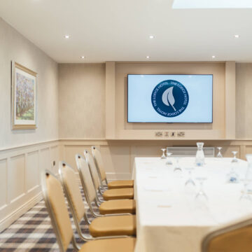 Elegant conference room with tech amenities, spacious seating, natural light, and modern decor, perfect for business meetings.