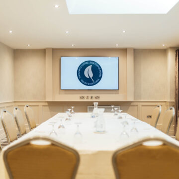 Spacious hotel meeting room with elegant seating, natural light, and modern audiovisual setup for successful events.