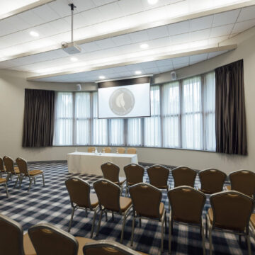 Spacious conference room with elegant seating, natural light from large windows, and modern presentation equipment.