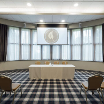 Modern conference room with large windows, projector, and seating at a luxury hotel ideal for business meetings.